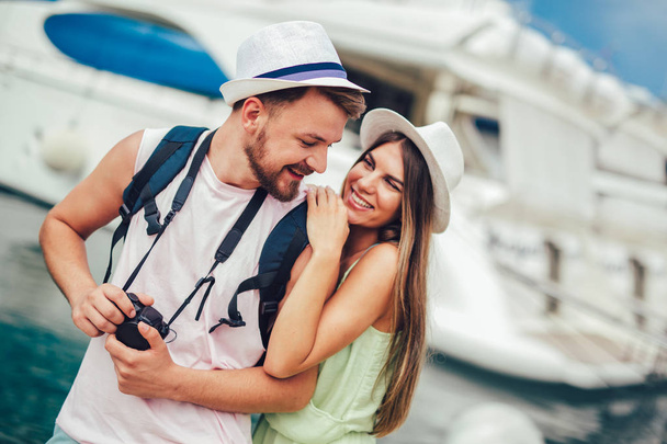 Couple de voyageurs marchant et se câlinant dans la station balnéaire près de yachts
.  - Photo, image