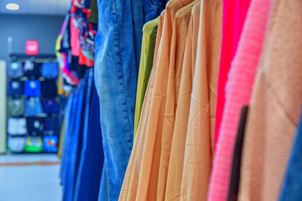 Πολύχρωμο γυναικεία φορέματα στις κρεμάστρες σε ένα κατάστημα λιανικής πώλησης. Μόδα και εμπορική έννοια.  - Φωτογραφία, εικόνα