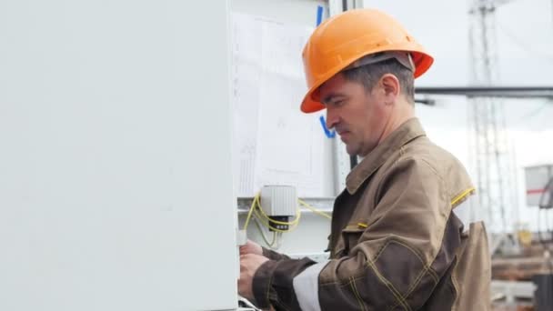 electrician mounts details on switchgear in premises at window - Felvétel, videó