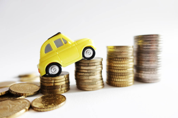 Costo creciente para el concepto de funcionamiento del coche con coche amarillo en miniatura en la pila de dinero en efectivo
 - Foto, imagen