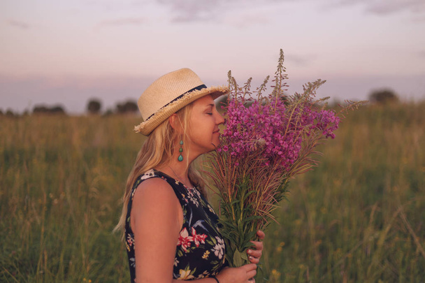 Girl in a field of flowers enjoys nature at the sunset. - Fotoğraf, Görsel