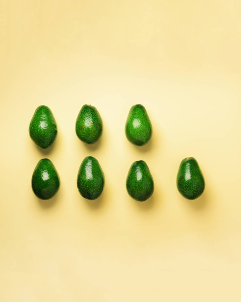 Sarı zemin üzerine yeşil avokado desen. Üstten görünüm. Pop sanat tasarım, yaratıcı yaz gıda kavramı. Organik avocadoes en az daire yatıyordu tarzı. - Fotoğraf, Görsel