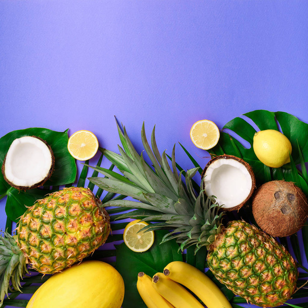 Piñas exóticas, cocos, plátano, melón, limón, palma tropical y hojas de monstera verde sobre fondo amarillo, violeta con copyspace. Diseño creativo. Concepto de verano monocromo. Piso tendido, vista superior
. - Foto, imagen