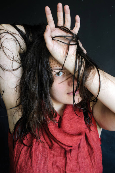 πορτρέτο φωτογραφία εικόνα ενός κοριτσιού με έθνικ μοτίβα στο πρόσωπό της σε κόκκινα ρούχα σκούρα μαλλιά κρατά στα χέρια της σαν ένας σαμάνος - Φωτογραφία, εικόνα