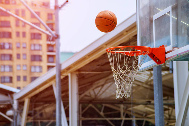 Action shot of basketball falls through basketball hoop and net on park background - Photo, Image