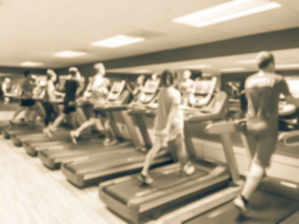 Vintage blurred abstract people running on treadmill at modern gym. 4-star hotel facility interior equipments in America. Busy fitness center with training exercise machines. - Photo, Image