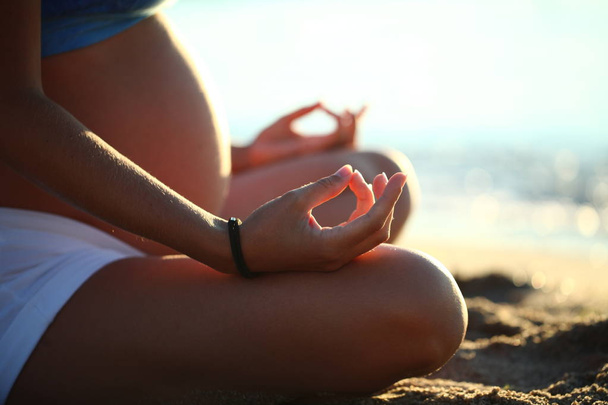 chica embarazada haciendo yoga arena playa mar
 - Foto, Imagen