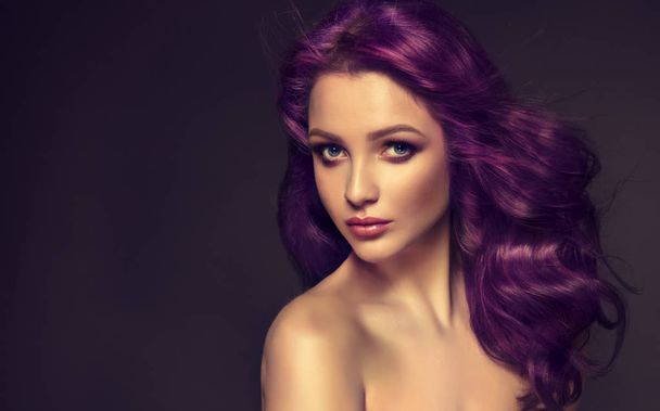 schönes Mädchen mit violettem, lockigem Haar auf dunklem Hintergrund - Foto, Bild