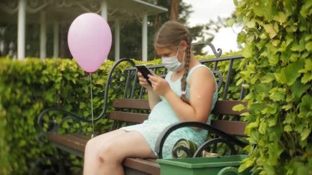 人工呼吸器でかわいい女の子がベンチの上の公園でタブレットを使用してください。 - 映像、動画