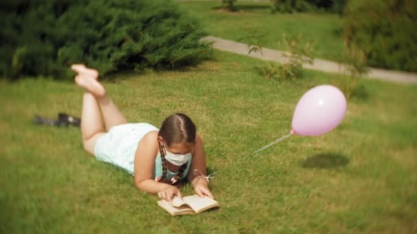 Menina bonito em um respirador lendo um livro no parque 4k
 - Filmagem, Vídeo