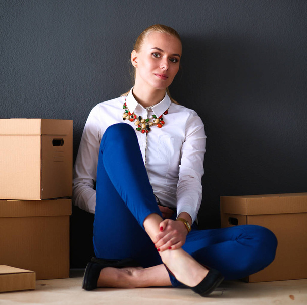 Woman sitting on the floor near a boxes  with laptop  - Photo, Image