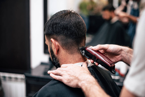 A man is hanging around in a beauty salon. Haircut and styling in barbershop. Men's care for beard and hair. - Foto, Bild