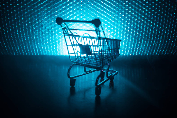 Empty shopping trolley on dark toned foggy background with some copy space. Financial crisis concept. - Фото, зображення