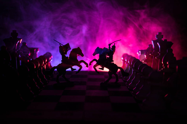 Cena de batalha medieval com cavalaria e infantaria no tabuleiro de xadrez. Conceito de jogo de tabuleiro de xadrez de ideias de negócios e concorrência e ideias de estratégia Figuras de xadrez em um fundo escuro com fumaça e nevoeiro
. - Foto, Imagem