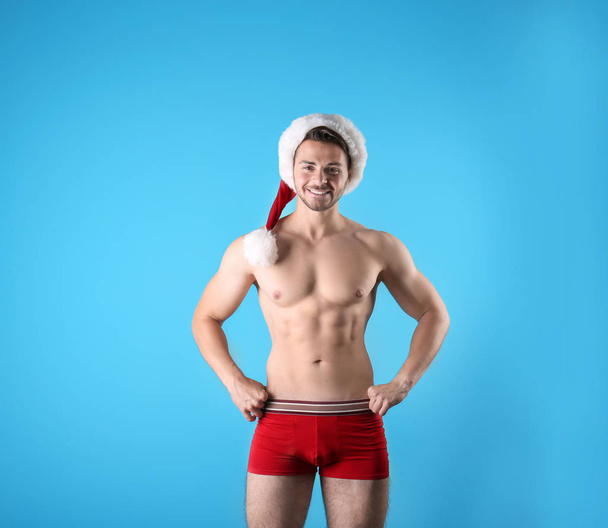 Shirtless young Santa Claus with sexy body on color background - Foto, Bild