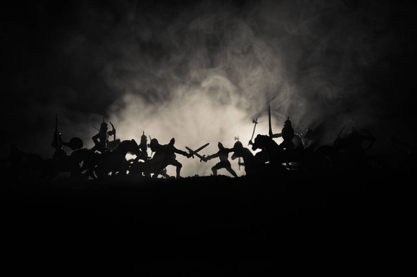 Středověká bitva scény s jezdectva a pěchoty. Siluety postav jako samostatné objekty, boj mezi bojovníky na tmavém tónovaný zamlžené pozadí. Noční scéna. Selektivní fokus - Fotografie, Obrázek