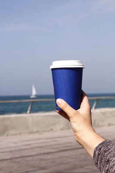 Blue paper cup with a drink on the background of the sea and the ship - Photo, Image