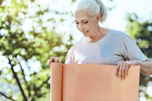 Concentrated senior woman holding a yoga mat - Photo, image