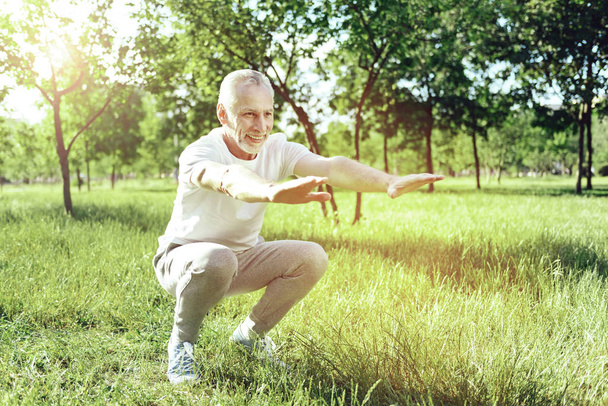 Smiling active aged man bending his knees - Photo, image