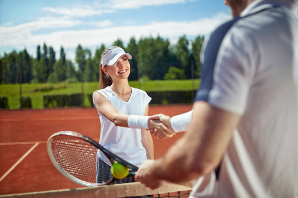 Young tennis player on tennis court shaking hands with opponent  - Foto, afbeelding