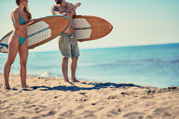Young man and woman with a surf board on the beach Vacation. Extreme Sport - Фото, изображение