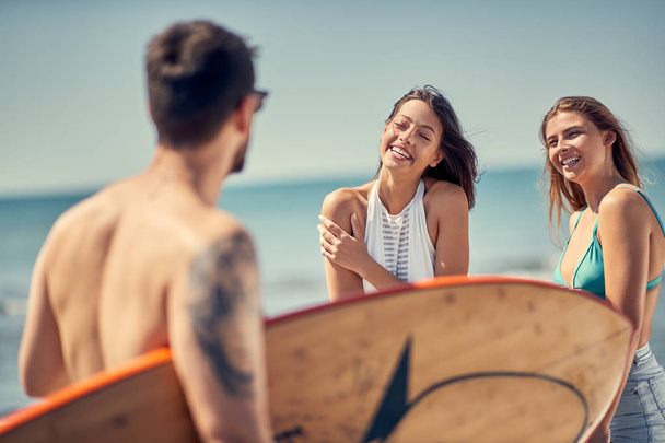 Grupo de jovens amigos felizes que vão surfar na praia
 - Foto, Imagem