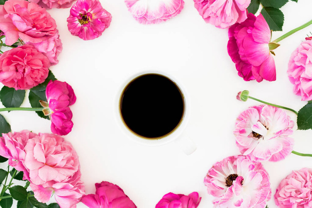 Marco de rosas rosadas y anémona con taza de café negro sobre fondo blanco. Piso tendido, vista superior. Textura flores
. - Foto, imagen