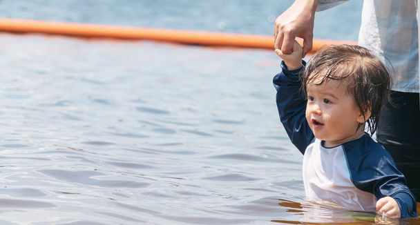 Toddler boy holding hands with his mother in a big lake - Foto, Bild