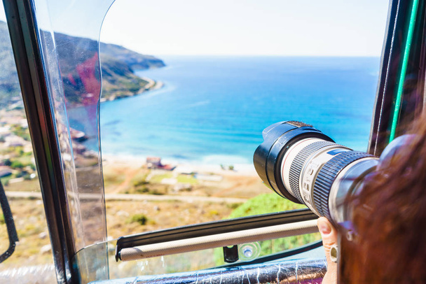 Nainen turisti istuu matkailuautossa ottamassa kuvaa kamera meressä. Kreikka Peloponnese
. - Valokuva, kuva