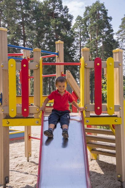 Happy two-year child on slide playground area. Boy 2 years on the playground. - Valokuva, kuva