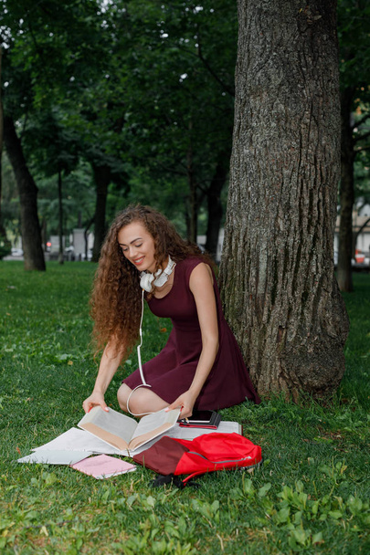 girl student holding book and sitting under tree - Photo, image