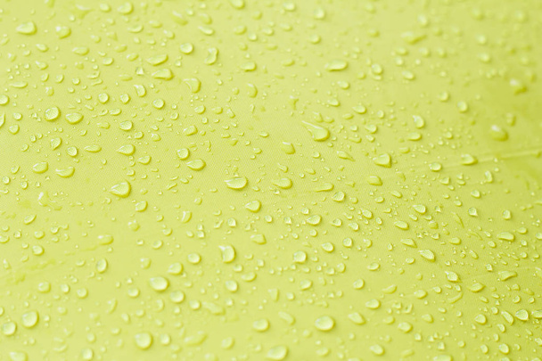 druppel water op gele achtergrond - Foto, afbeelding