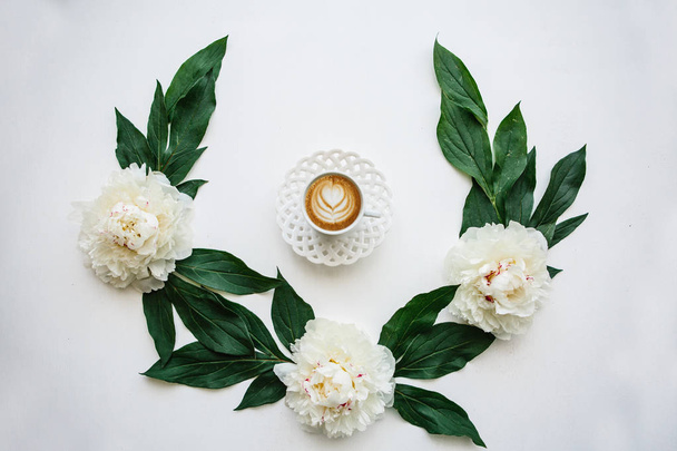Lahodné čerstvé cappuccino káva v hrnku s květinový vzor. Nedaleko leží krásné květiny pro dekoraci - Fotografie, Obrázek