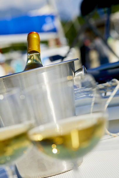 Pár wineglasses és fehér borosüveg jachton kosárral - Fotó, kép