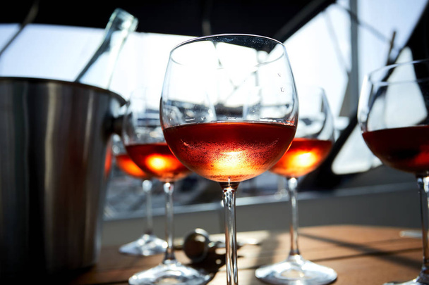 glasses of wine in bright sunlight on wooden surface - Foto, Bild