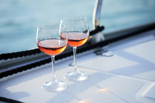glasses of wine in bright sunlight on yacht surface - Foto, Imagen