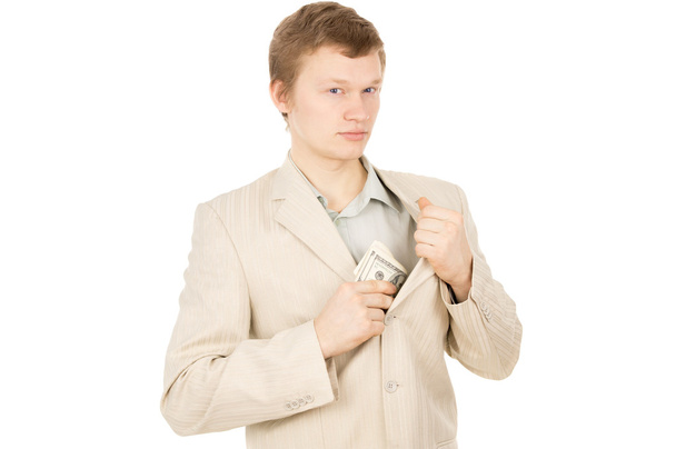 ένας όμορφος άντρας βάζει τα χρήματα στην τσέπη του και κοιτάζει γύρω από - Φωτογραφία, εικόνα