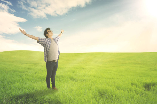 Hombre feliz con los brazos abiertos disfrutando de la primavera en el prado verde. Concepto de verano o primavera
 - Foto, imagen