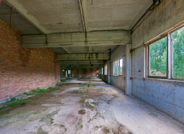 the building with a long concrete corridor overgrown with moss and windows has been thrown - Photo, Image