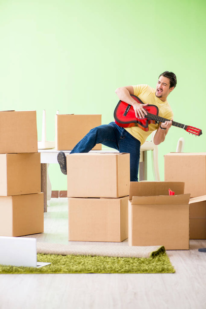Молодой красивый мужчина переезжает в новый дом с коробками - Фото, изображение