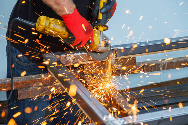 homens que trabalham com moedor de mão na construção de metal
  - Foto, Imagem