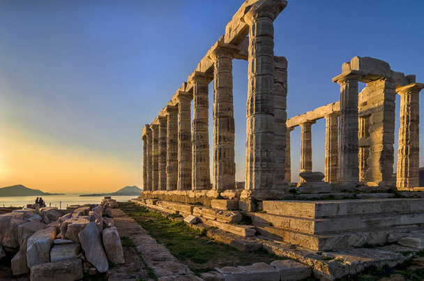 Sounion, Attica / Griekenland: kleurrijke zonsondergang bij Kaap Sounion en de ruïnes van de tempel van Poseidon met Patroklos eiland zichtbaar in de achtergrond. - Foto, afbeelding