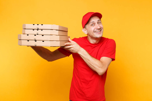 Delivery man in red cap, t-shirt giving food order pizza boxes isolated on yellow background. Male employee pizzaman or courier in uniform holding italian pizza in cardboard flatbox. Service concept - Фото, изображение