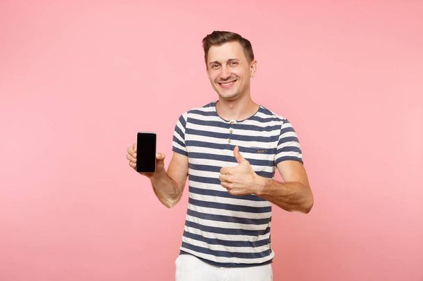 Portret van man in gestreept t-shirt weergegeven: mobiele telefooncamera met lege zwarte lege kopie schermruimte geïsoleerd op trend pastel roze achtergrond. Mensen oprechte emoties concept. Gebied van de reclame - Foto, afbeelding
