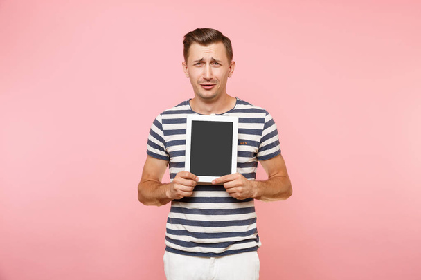 トレンドのパステル ピンクの背景に分離された空白の黒い空画面ディスプレイ タッチ スクリーン コピー スペースとタブレット コンピューターを保持している若い男の肖像画。技術ライフ スタイルのコンセプトです。広告エリア - 写真・画像