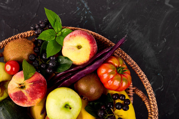 Egészséges színes ételeket: gyümölcs, zöldség, szuperétel, levél a kosár a sötét háttér előtt. Tiszta, eszik. Vegán. Méregtelenítés. Szupermarket termék. Választék friss organikus. Természetes koncepció  - Fotó, kép