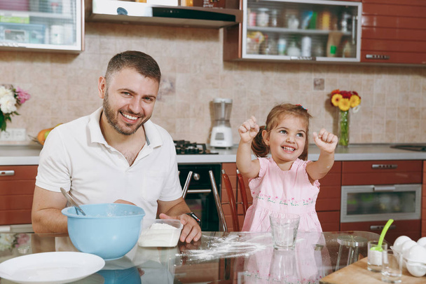 Dziecko dziewczynka pomaga człowiekowi gotować ciasteczka świąteczne imbir i pokropienie mąki przy stole. Szczęśliwa rodzina tata, córka dziecko gotowanie żywności w weekend rano. Wakacyjny dzień ojca. Dzieciństwa rodzicielstwa - Zdjęcie, obraz