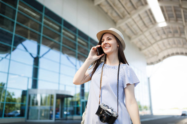 Young traveler tourist woman with retro vintage photo camera talking on mobile phone calling friend, booking taxi, hotel at airport. Passenger traveling abroad on weekends getaway. Air flight concept - Photo, Image