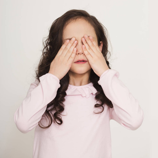 Mała dziewczynka zasłania oczy dłońmi - Zdjęcie, obraz