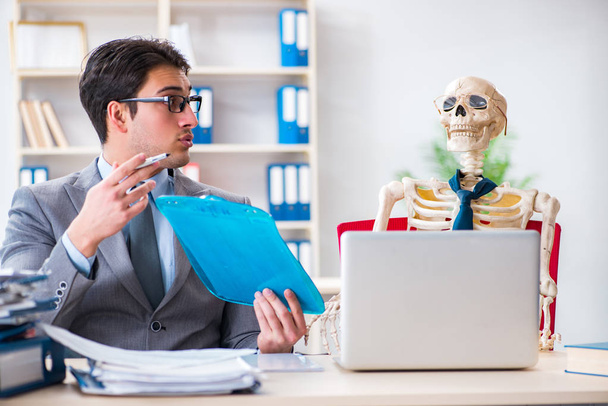 Biznesmen pracujący ze szkieletem w biurze - Zdjęcie, obraz
